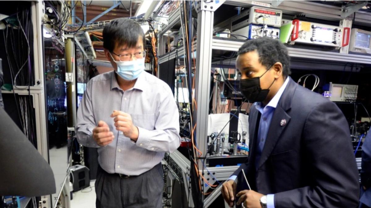Rep. Neguse and physicist Jun Ye stand in a laboratory as Ye explains how the recent infrastructure bill allowed for JILA to succeed. 